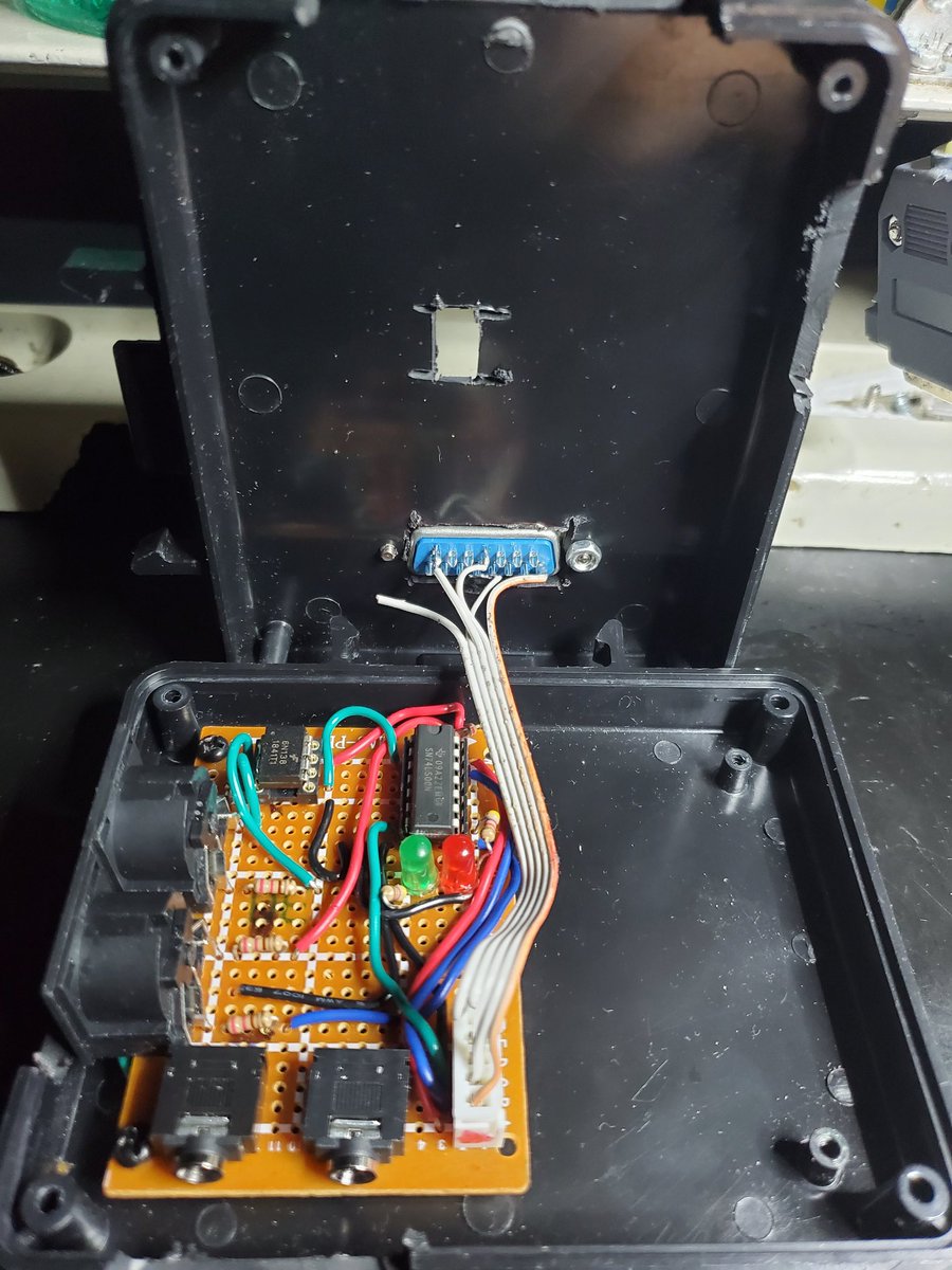 The inside of the box, the D-shell connector connects to a JST connector on a perfboard, on which is mounted the two sets of MIDI out/in connectors (DIN and 3.5 miniplug) and some LEDs and ICs.