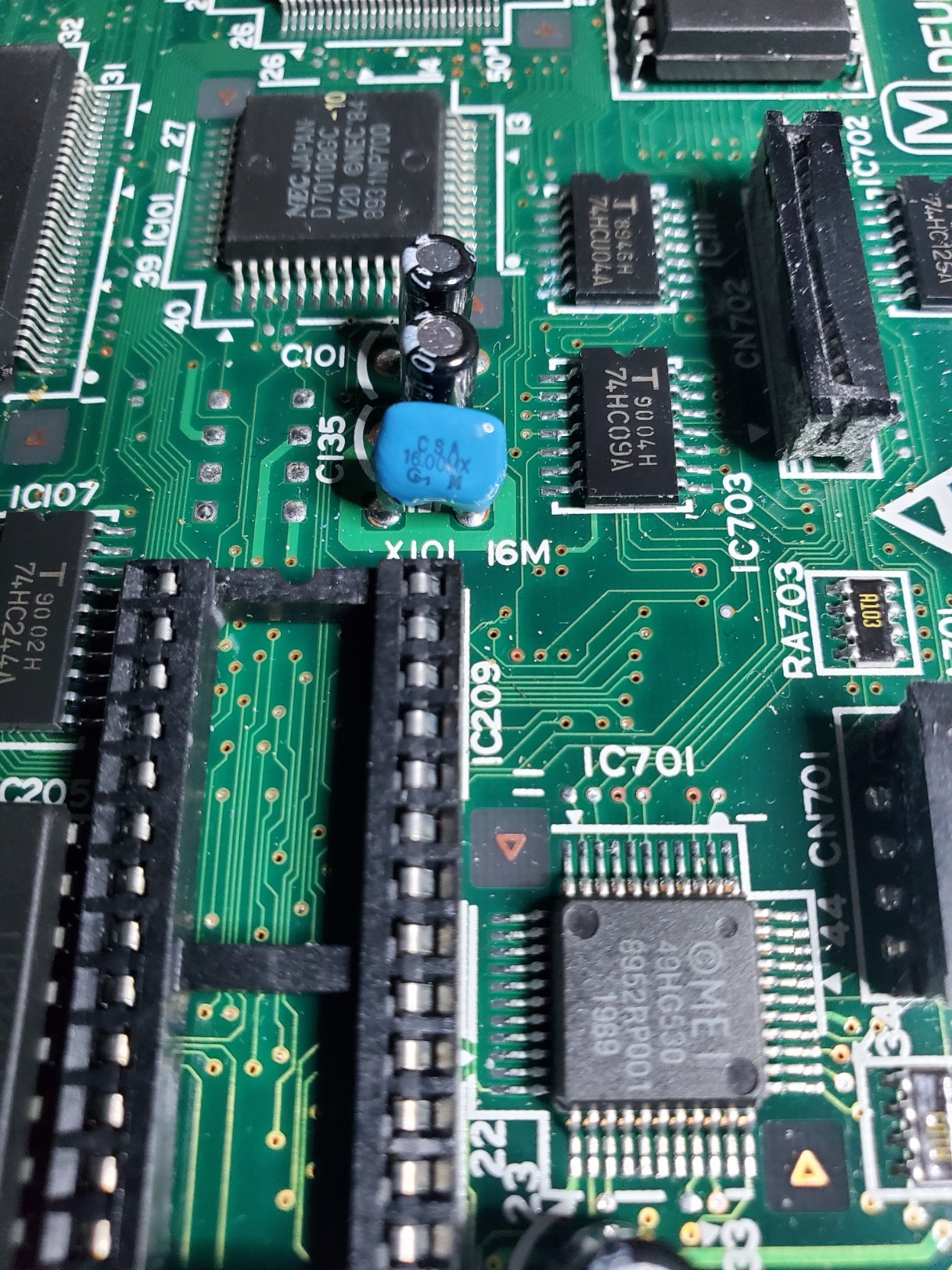 Closeup of the original clock chip in a bright blue package near the ROM socket. Practically invisible is the crack around one of the legs in the blue package.