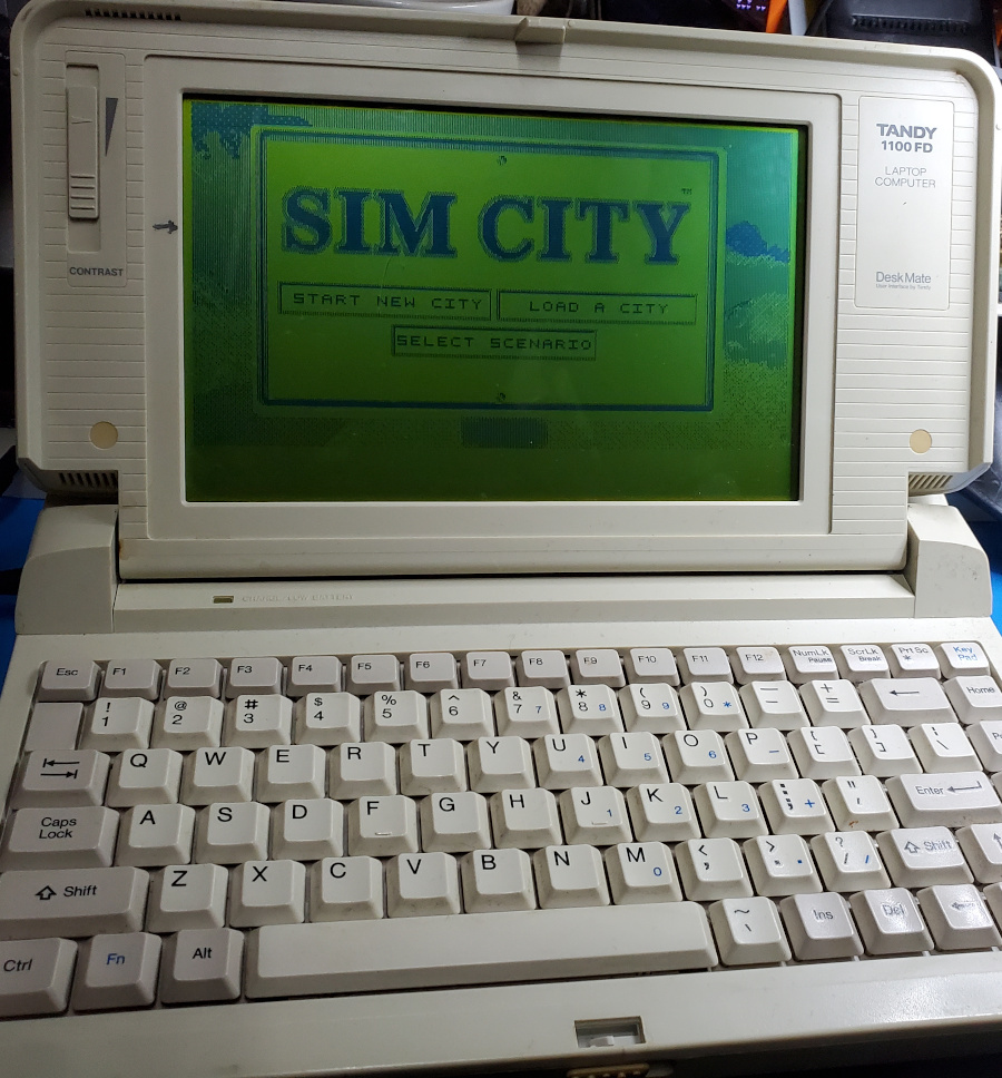 Tandy 1100FD displaying the SimCity title screen in monochrome green/black.