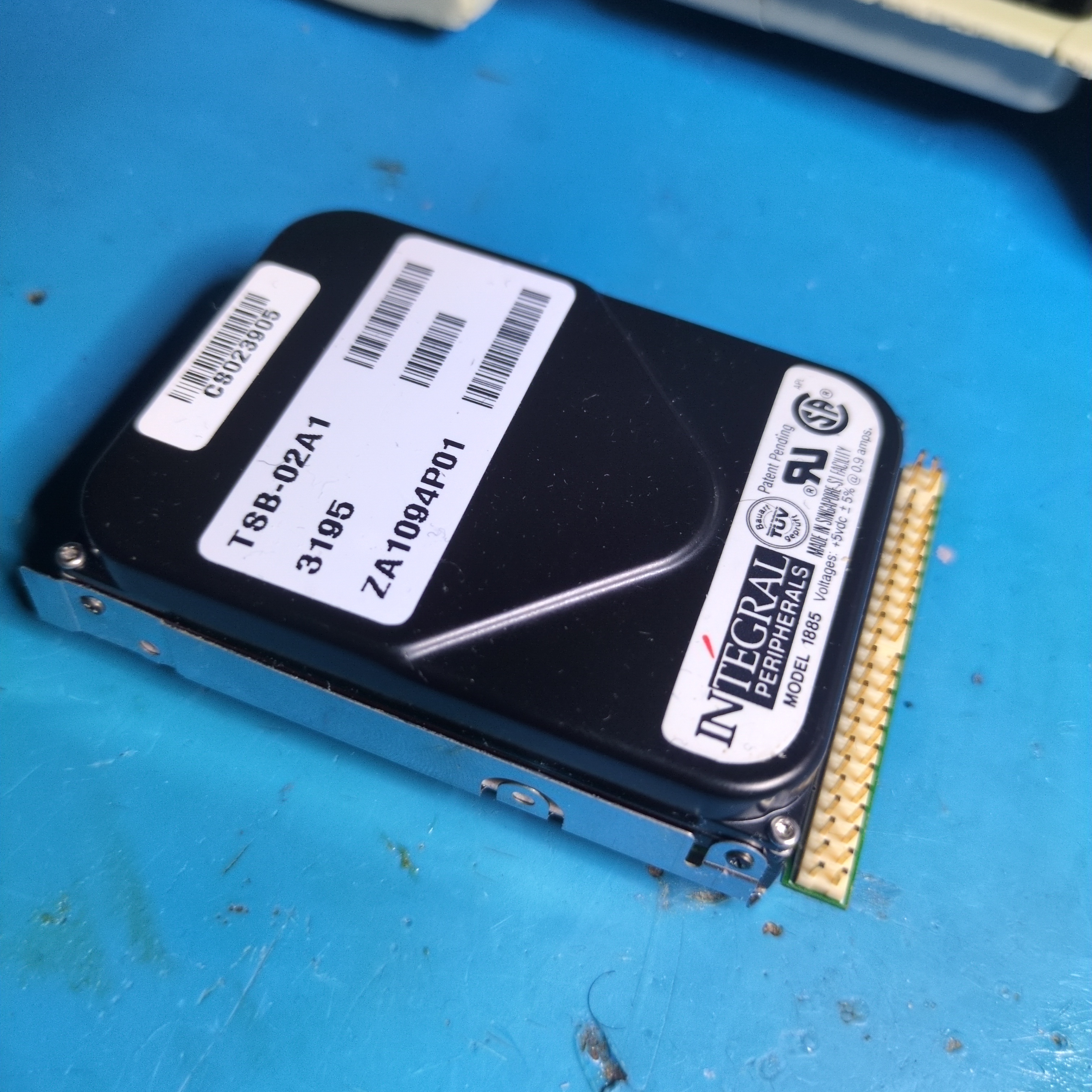 Photograph of a computer hard disk. It has the peculiar characteristic of an IDE connector pointed perpendicular to its length, unlike most disks.